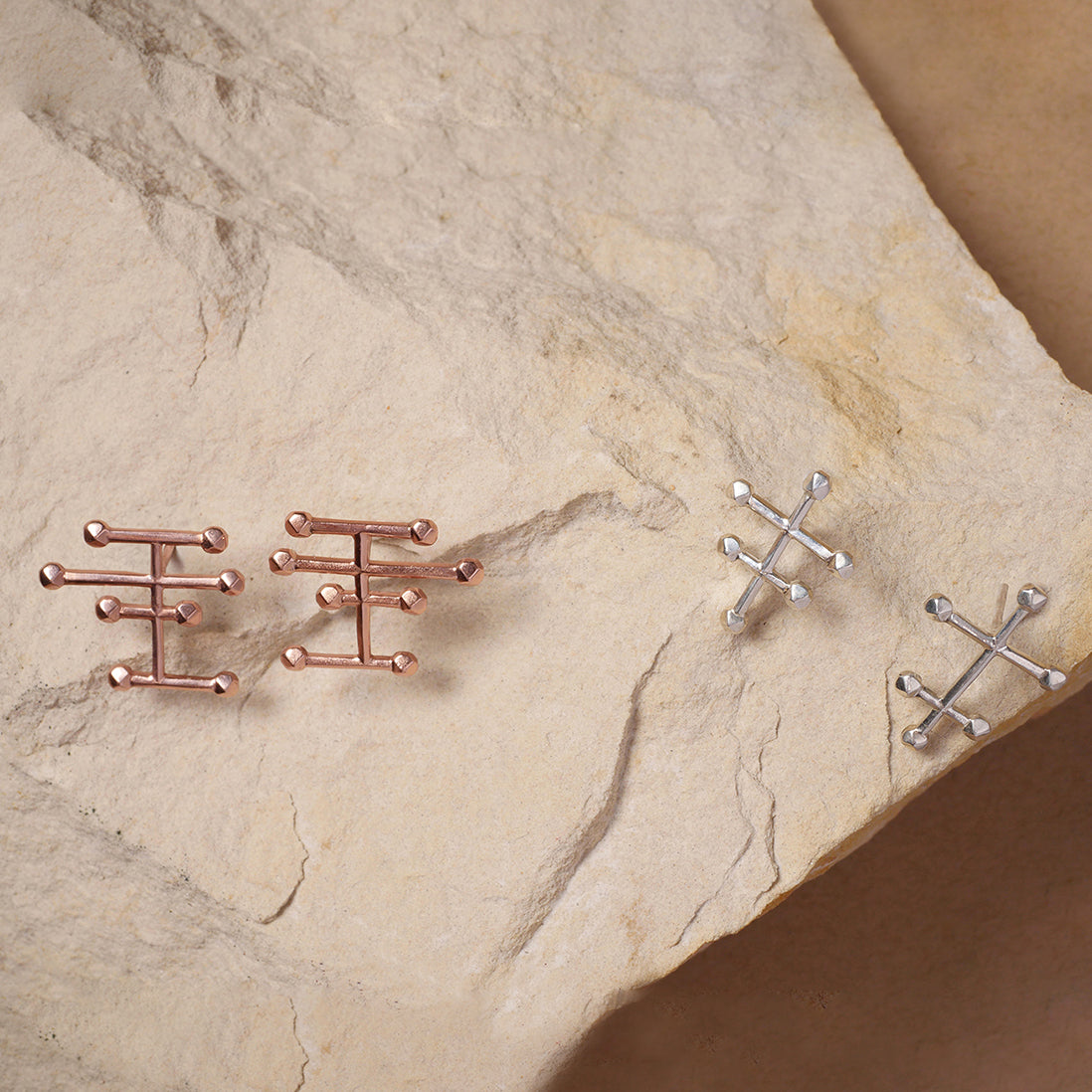 Aretes Taches mini en plata y con enchape de oro rosado, foto ambientada con piedra. Joyería de autor, hecho en Colombia por Mariana Shuk.