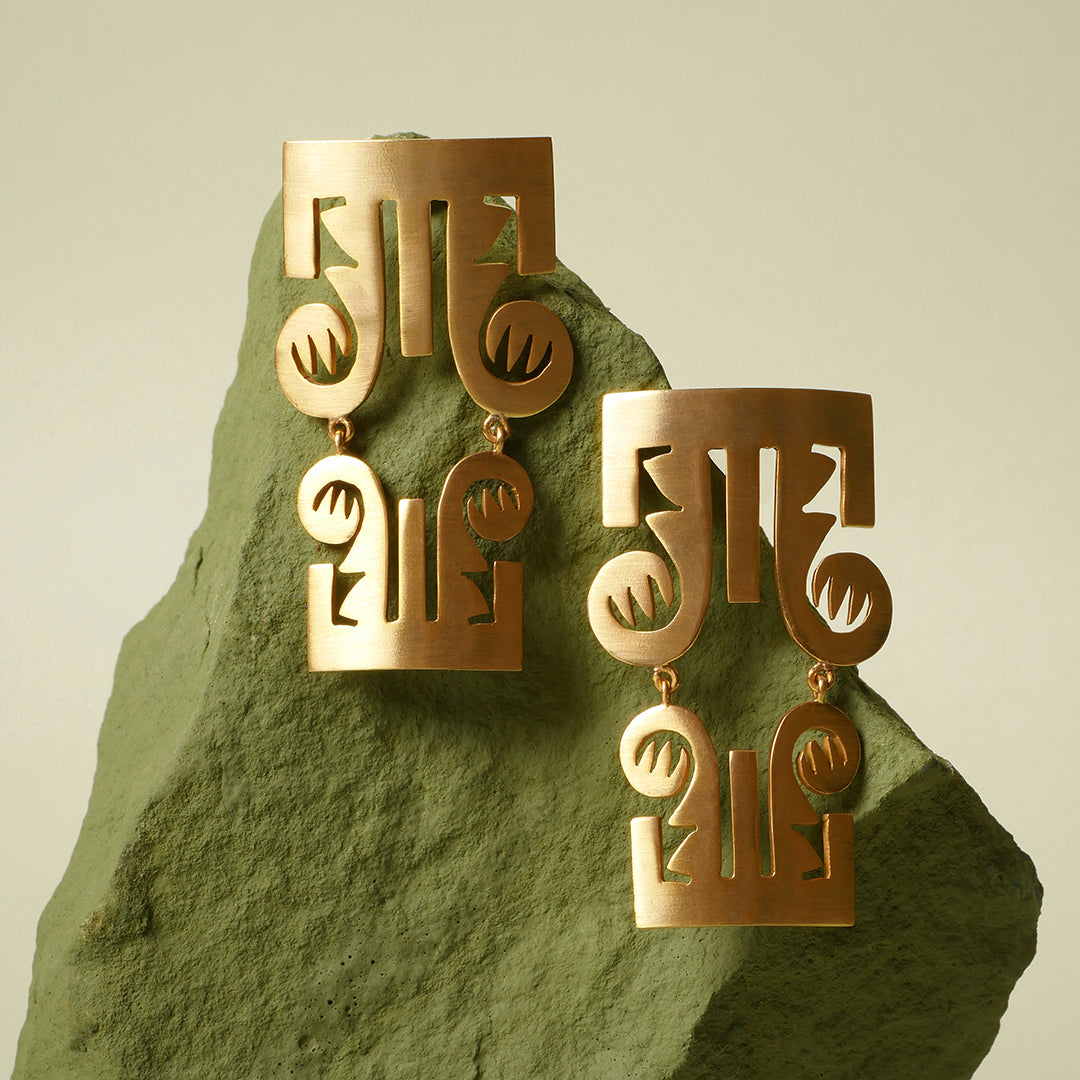 Aretes trompas precolombino en plata con enchape oro amarillo, foto con vista frontal ambientada. Joyería artesanal inspirada en arte precolombino. Diseños exclusivos, hecho en Colombia por Mariana Shuk.