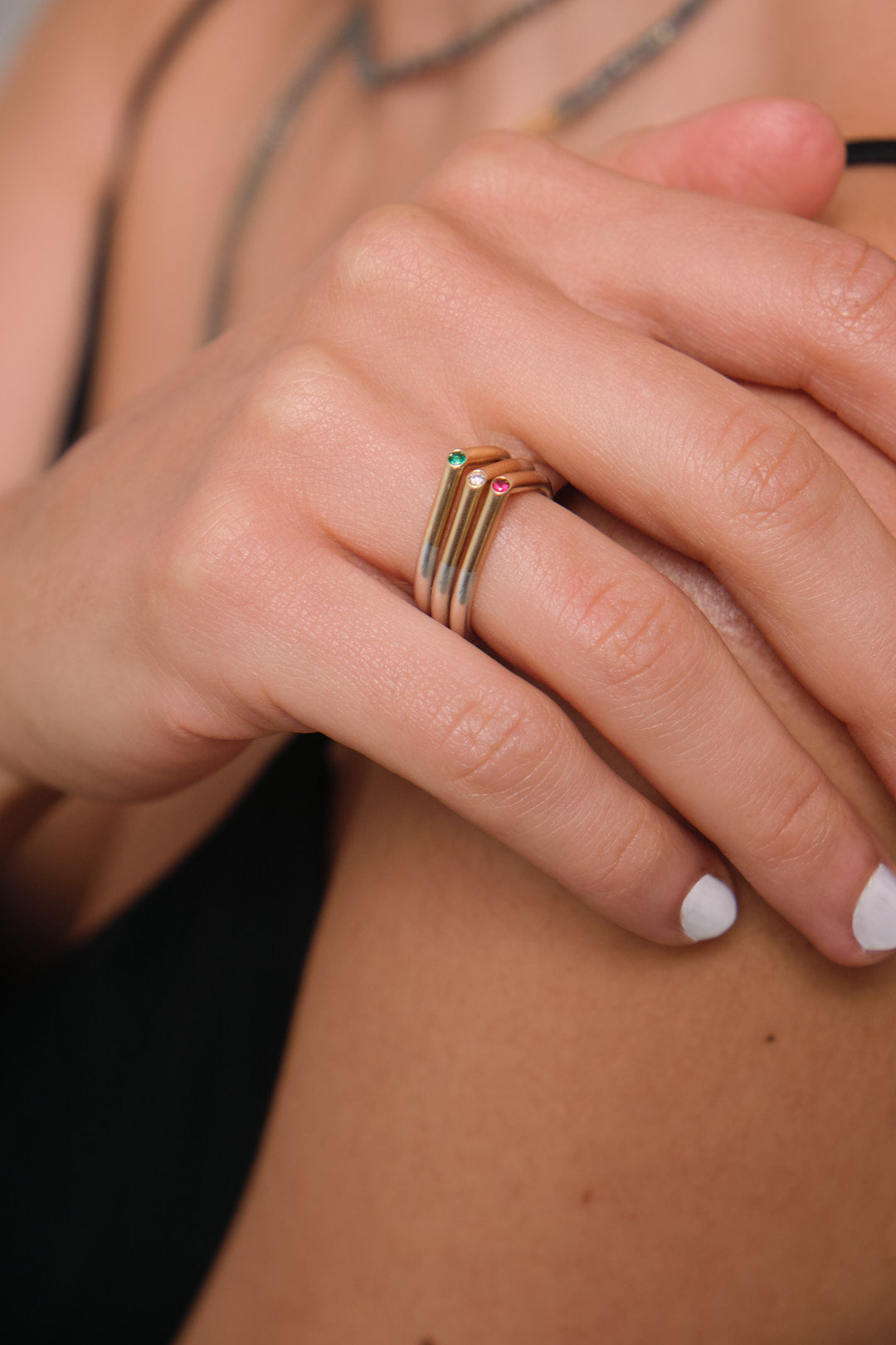 Anillo de matrimonio en plata 0.925 y oro amarillo 18k con esmeralda de 0.025 ct, diamante blanco u ruby. Vista con modelo y tres opciones de anillos, alta joyería de autor hecha a mano en Colombia.