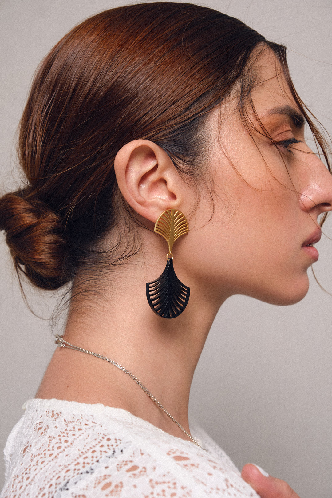 Pendientes de plata 925 palma deco con enchape de oro y acrílico negro, vista con modelo. Joyería de autor, hecho en Colombia por Mariana Shuk.