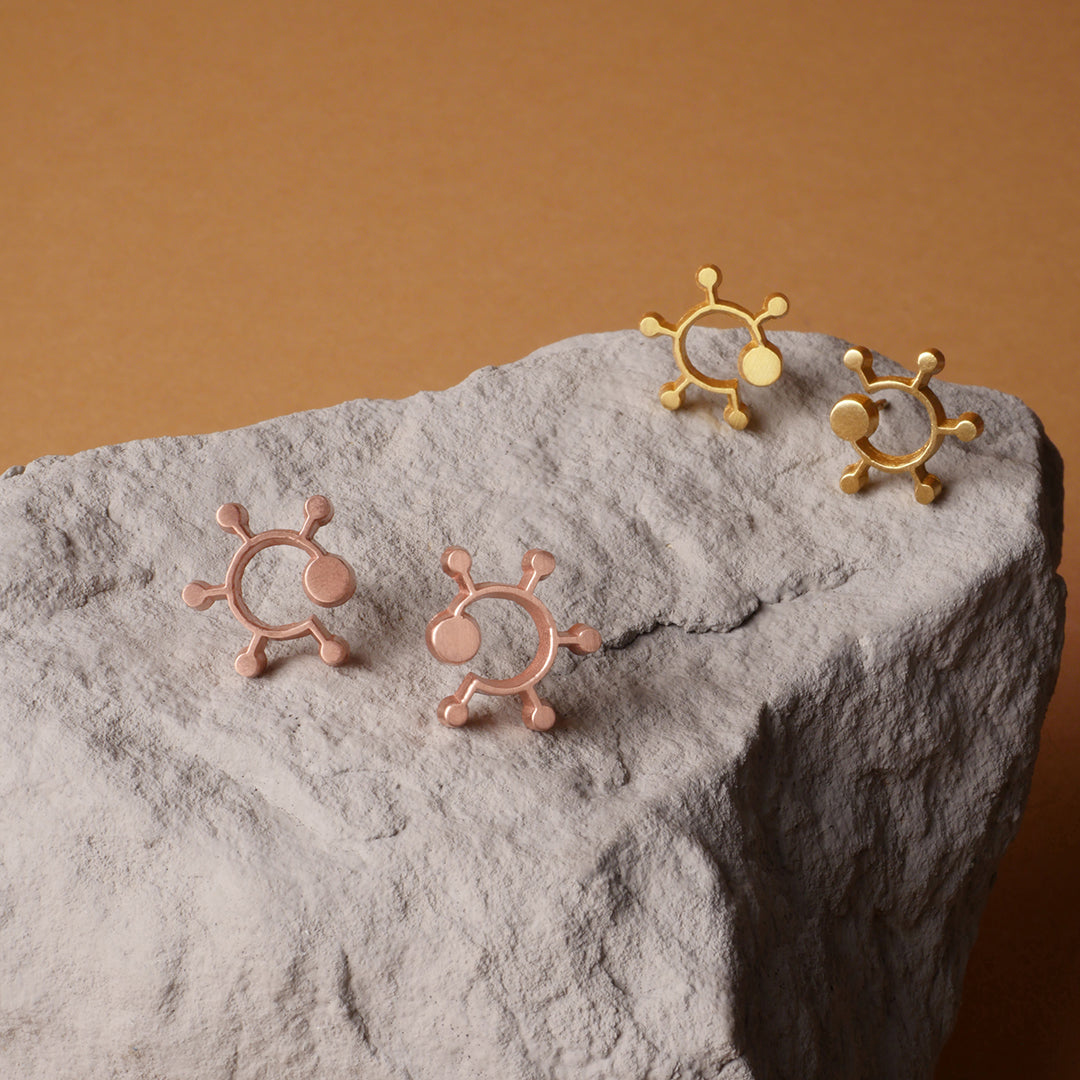 Aretes espiral curvas y puntos en plata 925, con enchape de oro amarillo y oro rodao, foto con vista frontal ambientada. Joyería artesanal inspirada en la naturaleza, hecho en Colombia por Mariana Shuk.