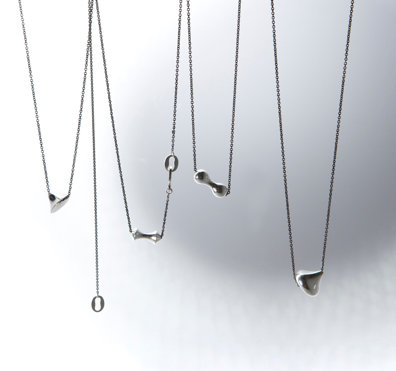 Dijes sólidos en plata, foto con vista frontal. Joyería artesanal inspirada en simetría y elegancia. Diseños exclusivos, hecho en Colombia por Mariana Shuk.