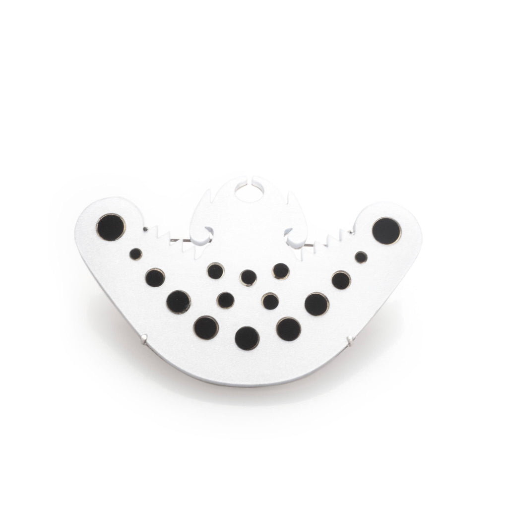 Broche murciélago precolombino B/N en acrílico blanco perlescente y negro, foto con vista frontal. Joyería artesanal inspirada en arte precolombino. Diseños exclusivos, hecho en Colombia por Mariana Shuk.