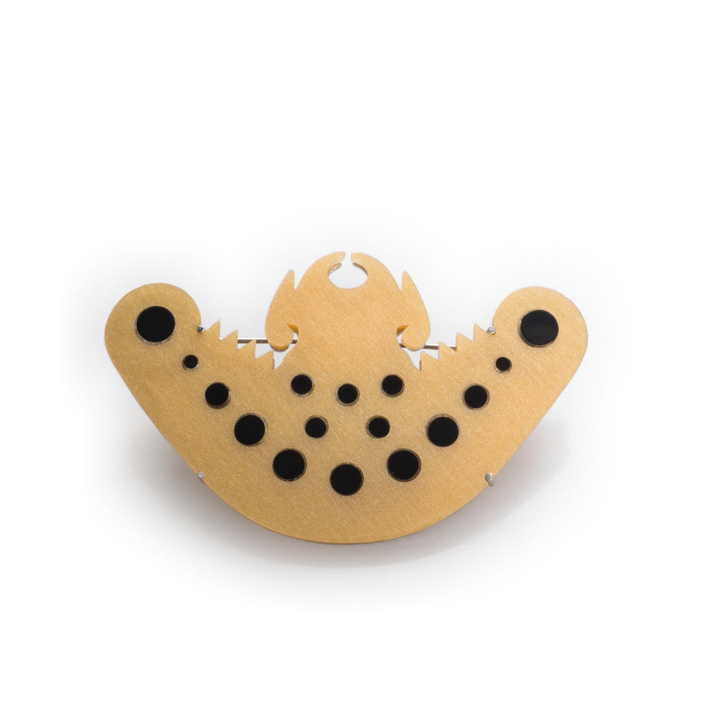 Broche murciélago precolombino D/N en acrílico dorado perlescente y negro, foto con vista frontal. Joyería artesanal inspirada en arte precolombino. Diseños exclusivos, hecho en Colombia por Mariana Shuk.