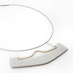 Collar con dije vuelo abierto en acrílico perlado blanco, foto con vista frontal. Joyería artesanal contemporánea inspirada en arte precolombino. Diseños exclusivos, hecho en Colombia por Mariana Shuk.