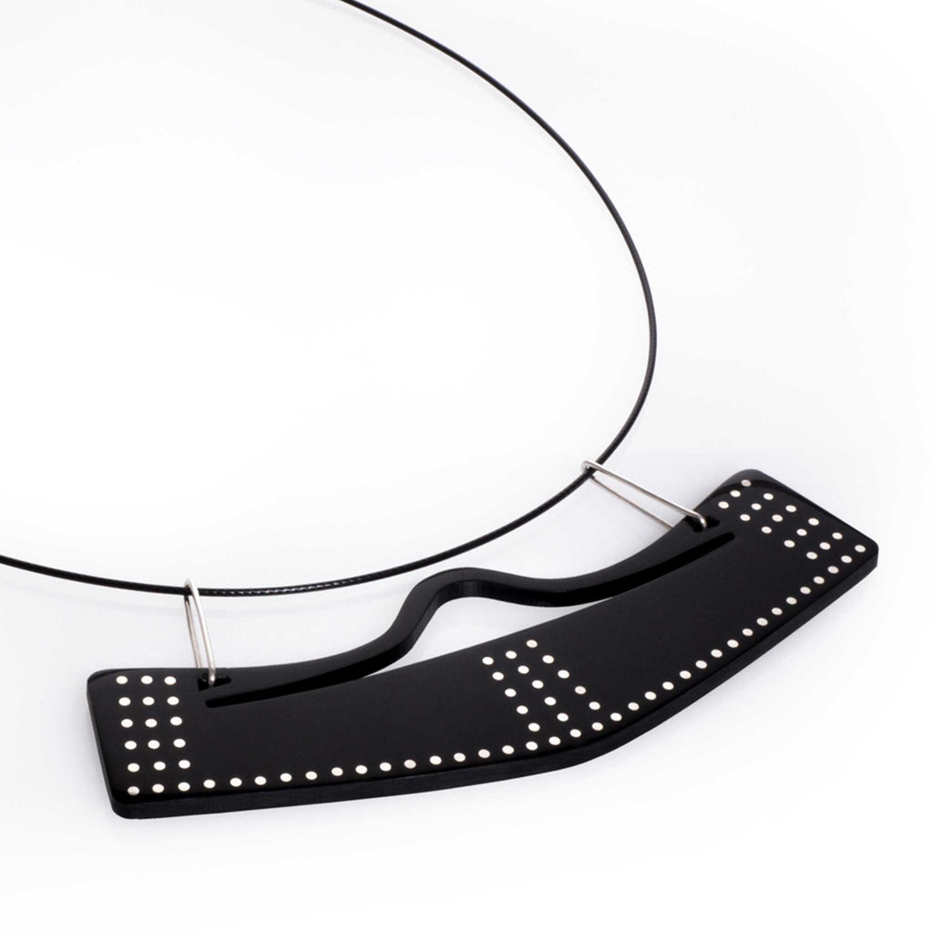 Collar con dije vuelo abierto en acrílico negro, foto con vista frontal. Joyería artesanal contemporánea con diseño inspirado en movimiento y equilibrio. Diseños exclusivos, hecho en Colombia por Mariana Shuk.