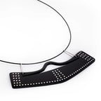 Collar con dije vuelo abierto en acrílico negro, foto con vista frontal. Joyería artesanal contemporánea con diseño inspirado en movimiento y equilibrio. Diseños exclusivos, hecho en Colombia por Mariana Shuk.