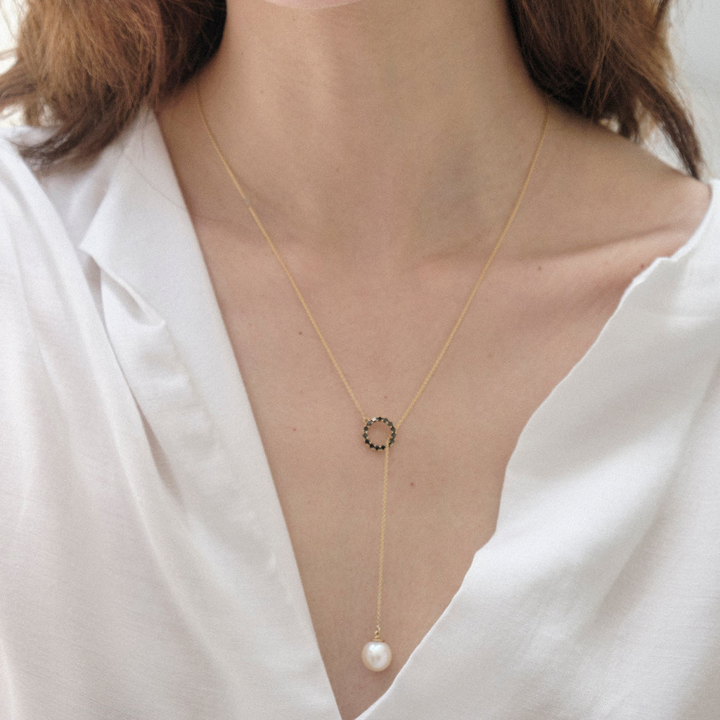 Dije en oro amarillo 18k con perla blanca de 8mm y diamantes negros, vista con modelo, joyería de autor hecha a mano en Colombia.