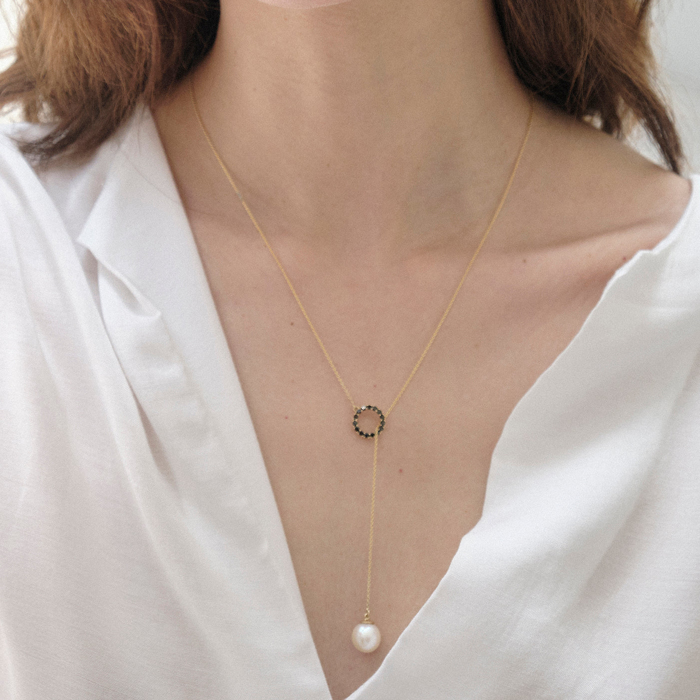 Dije en oro amarillo 18k con perla blanca de 8mm y diamantes negros, vista con modelo, joyería de autor hecha a mano en Colombia.